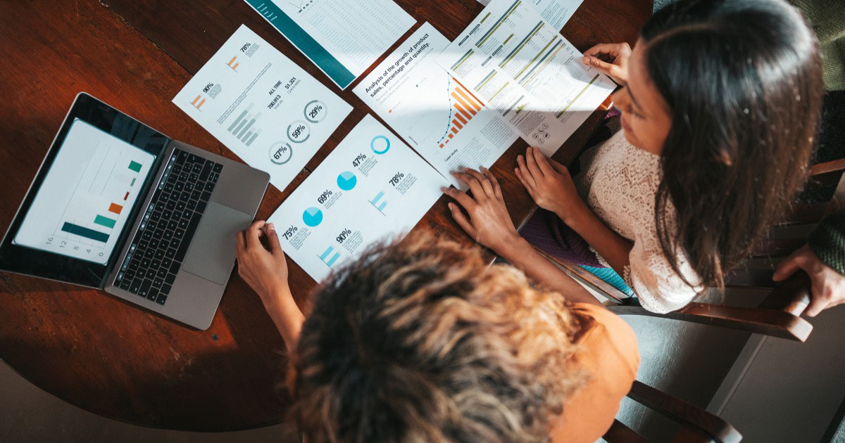 Two people sit at table reviewing documents