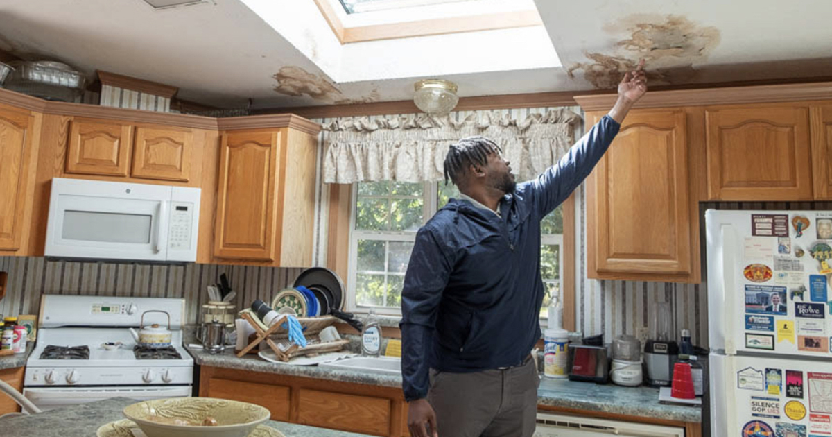 A man inspecting the ceiling in a kitchen