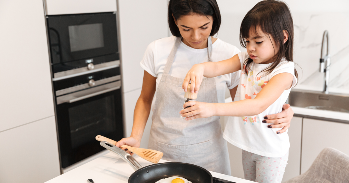 A photo of a mother and child cooking eggs in their kitchen