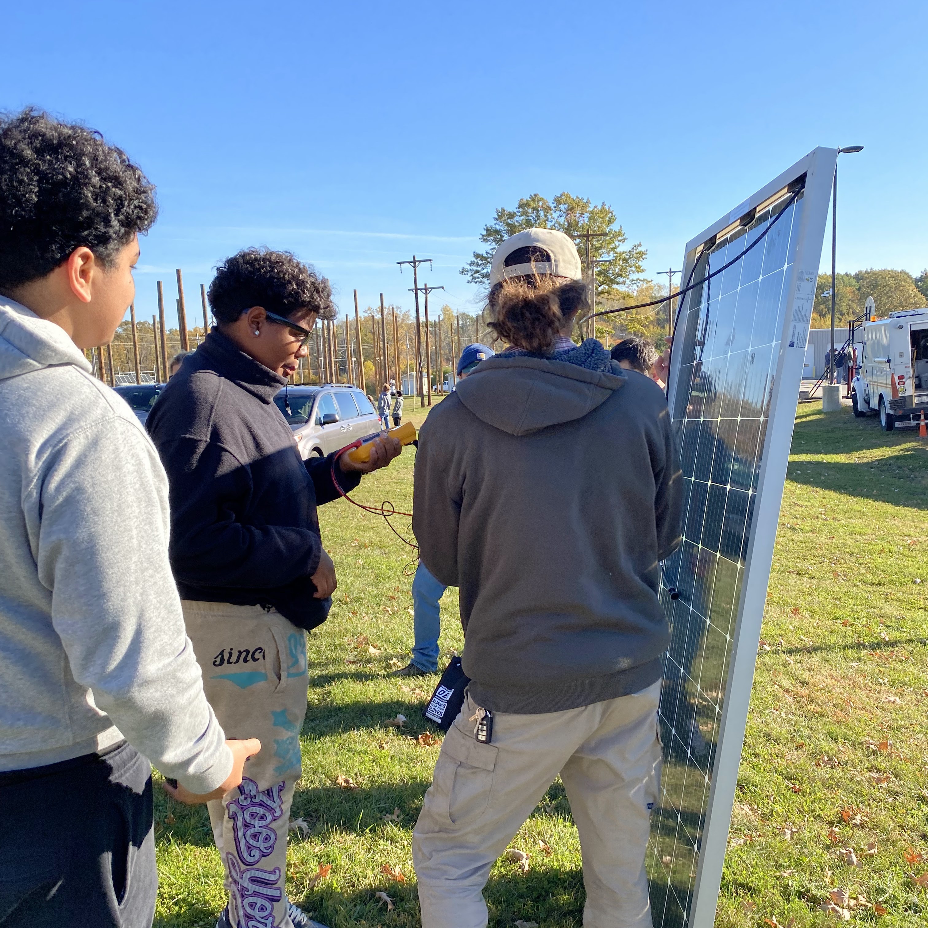 Students standing next to solar panels